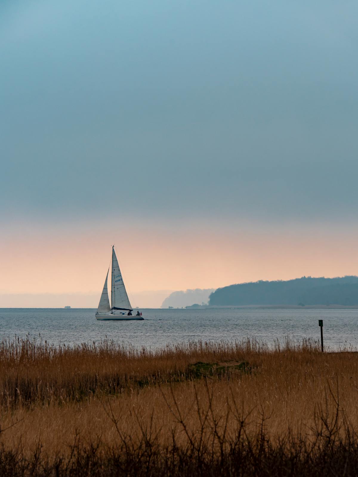 Yacht sailing at sunrise on calm water