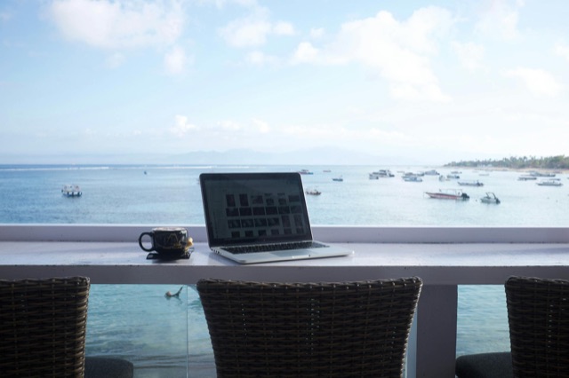 Person planning travel on a laptop with a view of the sea