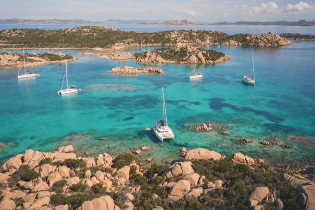 Boats anchored in a turquoise bay among granite rocks in the La Maddalena archipelago, seen from above