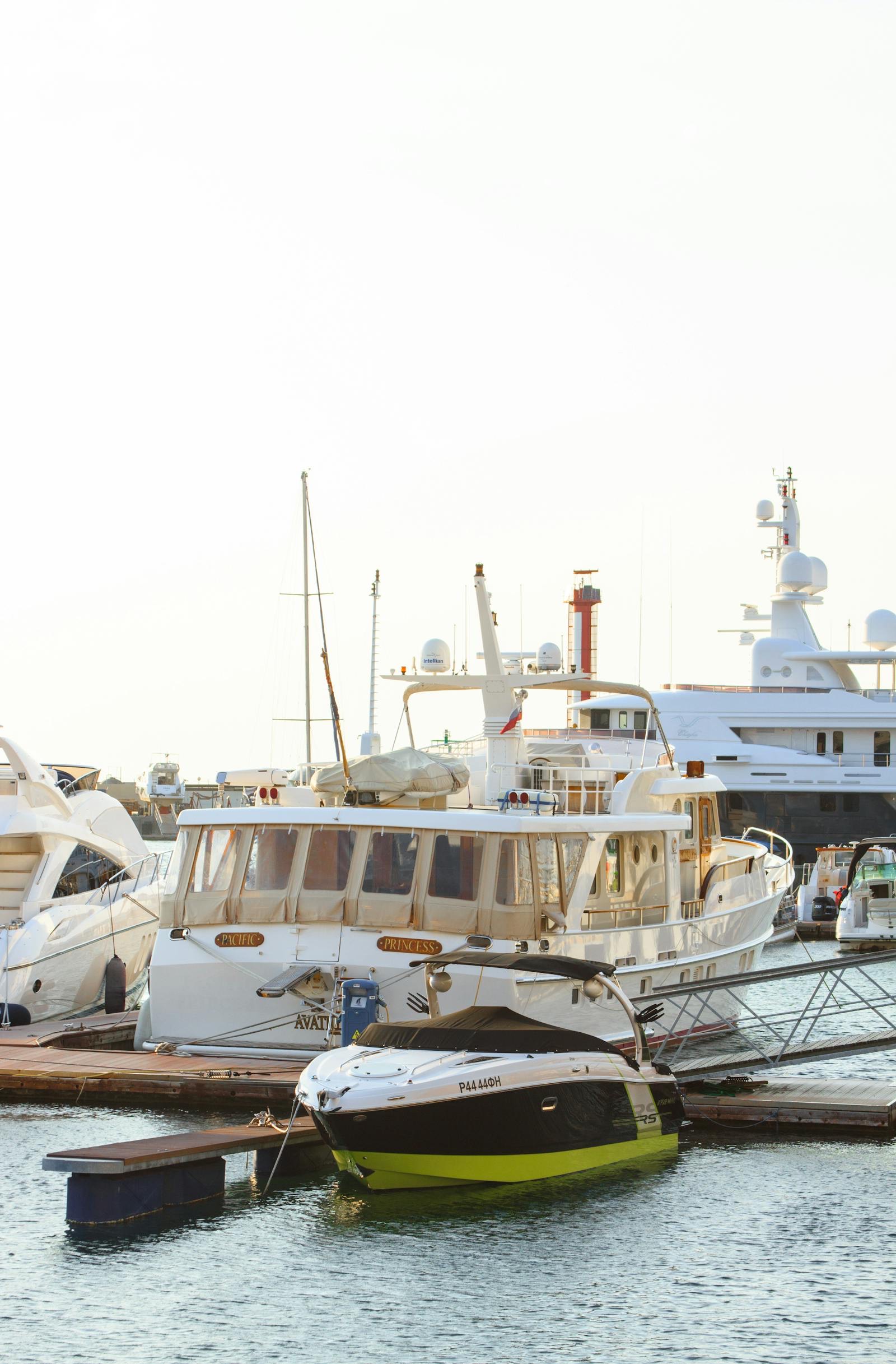 Yachts berthed stern-to along a marina quay with mountains behind