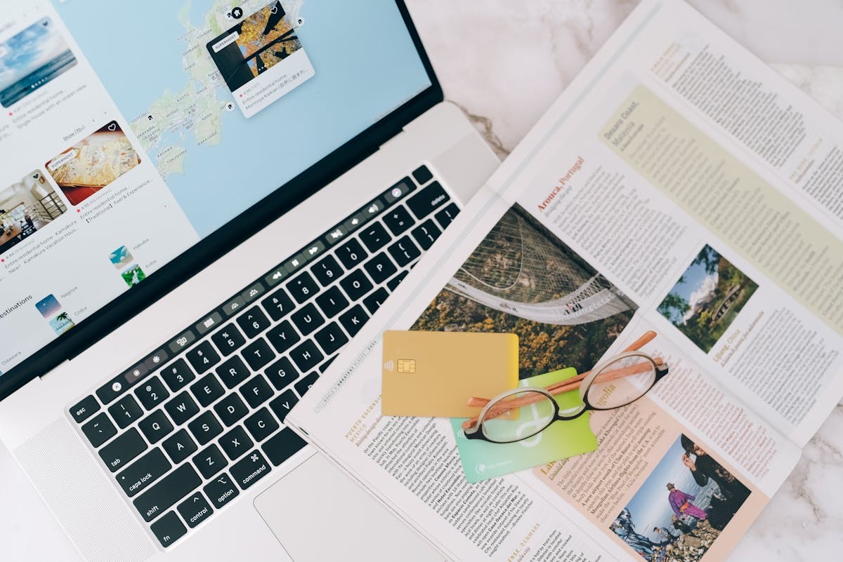 Laptop with travel magazine and credit card on a desk