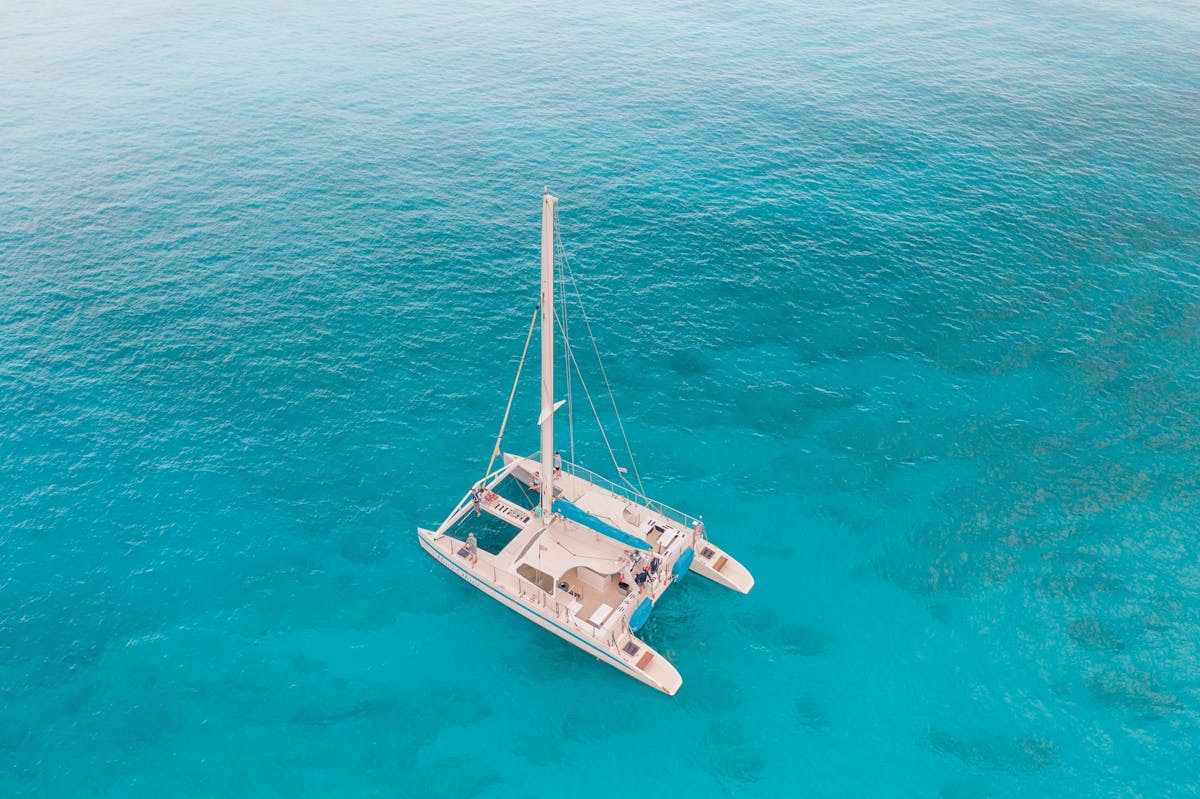 Catamaran anchored in turquoise water seen from above
