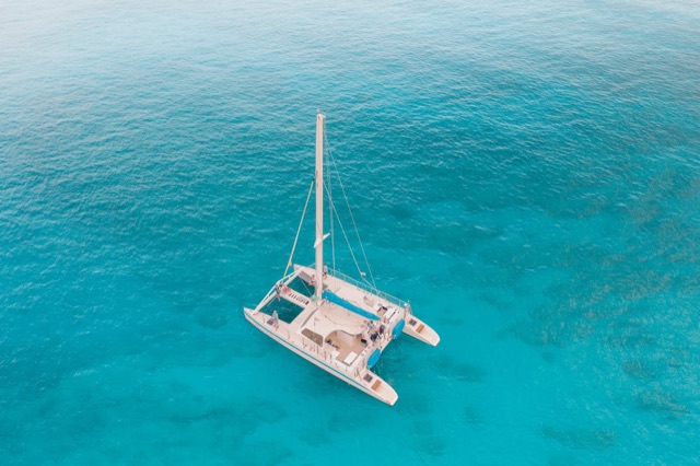Catamaran anchored in turquoise water seen from above